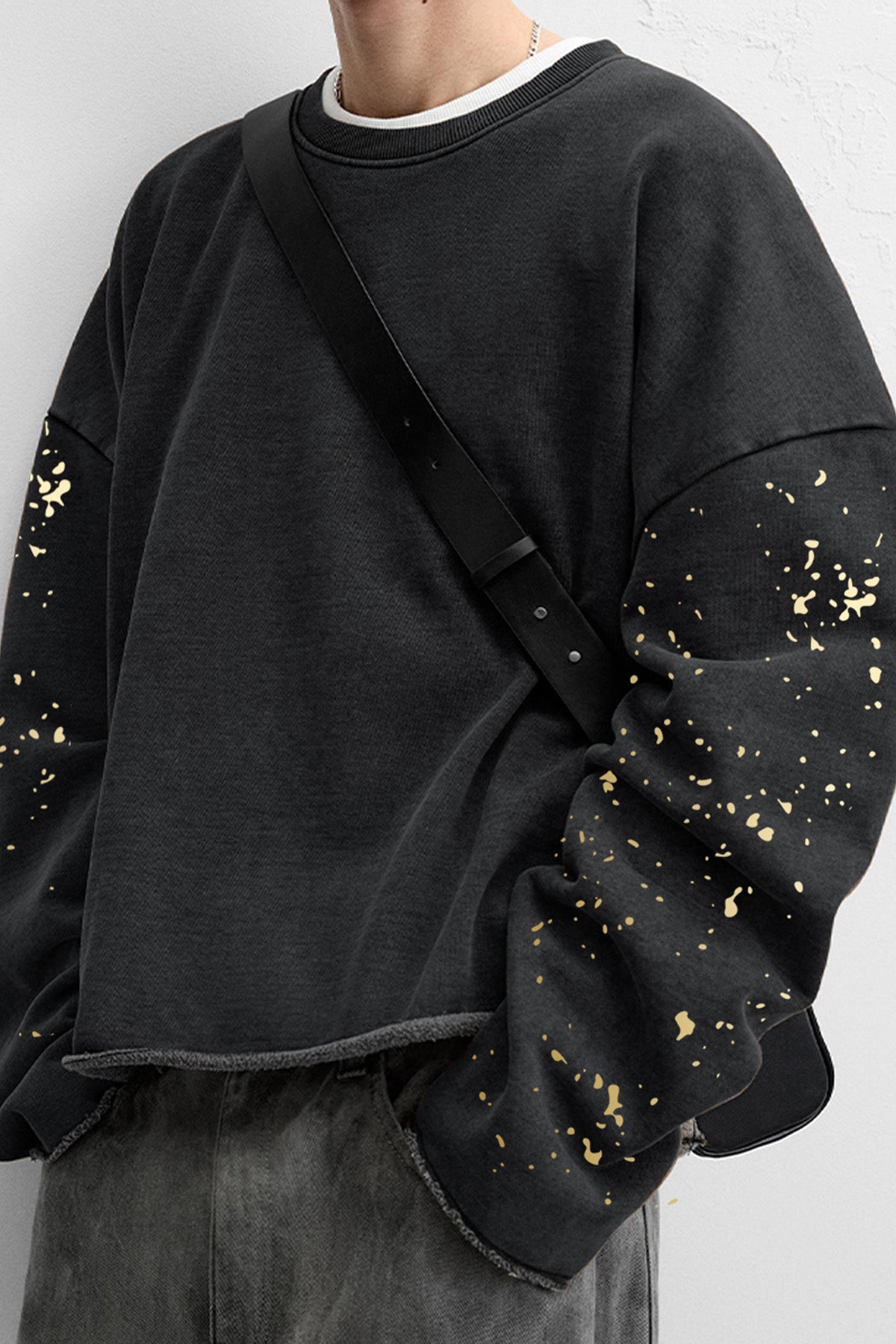 Close-up of gold splatter detailing on the sleeves of the Kaizo-Ku skull graphic sweatshirt.