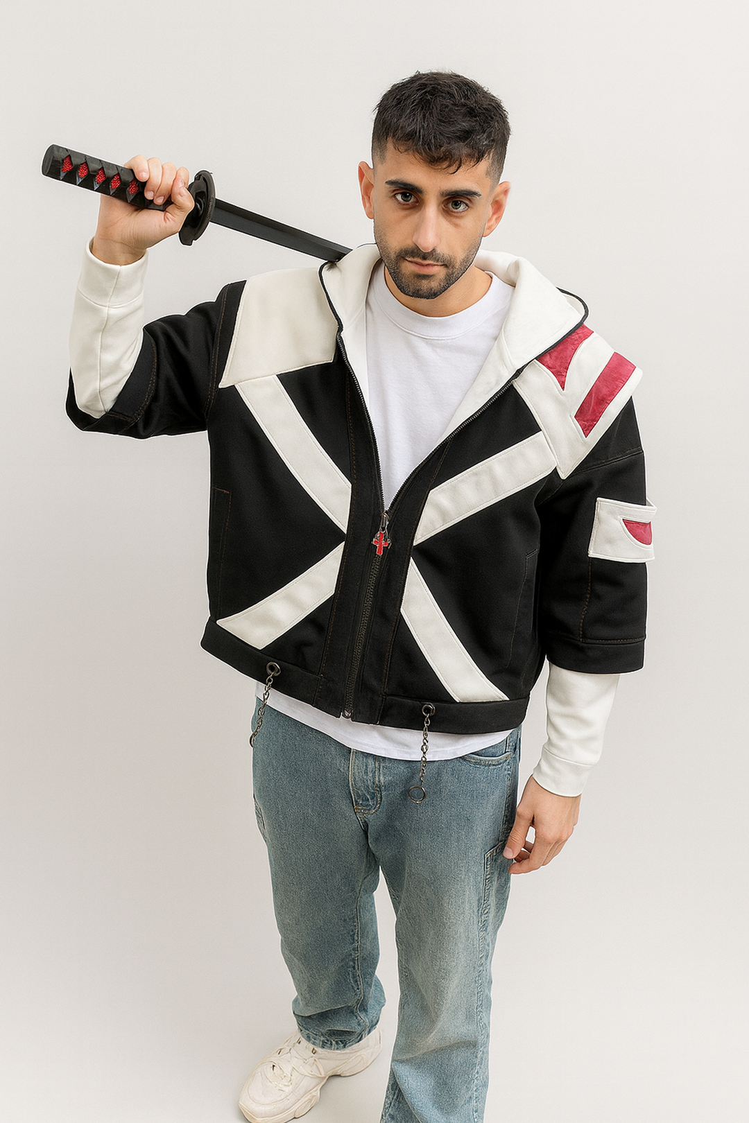 Le modèle porte le hoodie Ichigo True Shikai version streetwear, capuche relevée, avec le katana en main. On voit bien les panneaux blancs contrastés sur le denim noir et l’épaule en cuir rouge, parfait pour mettre en avant le côté héros de shonen dans la vraie vie.