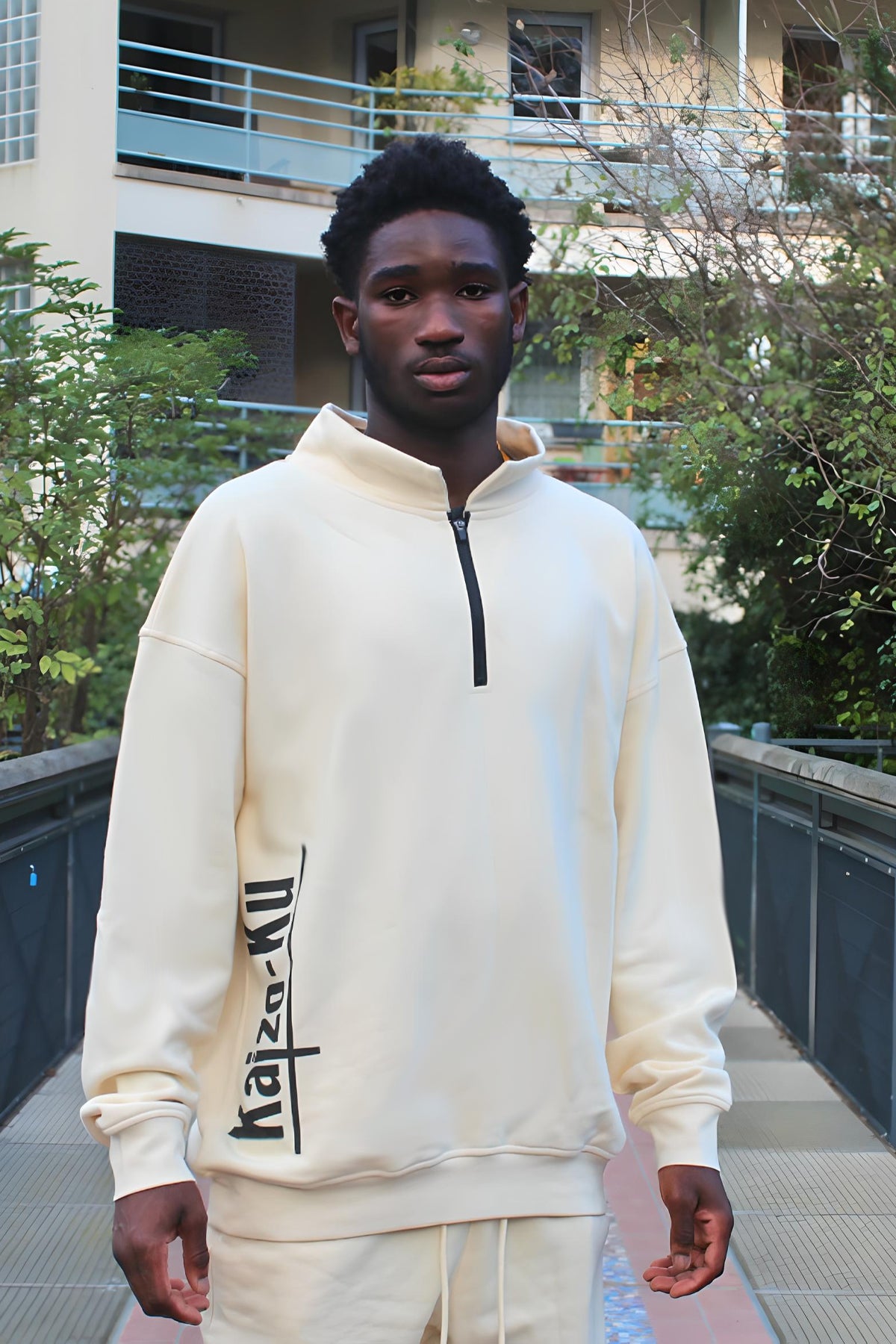 Male model wearing the Kaizo-Ku beige half-zipped sweatshirt, showcasing its relaxed fit and minimalistic style. The half-zip detail adds a touch of versatility, allowing for easy layering and adjustable comfort. Perfectly crafted for both style and warmth, this sweatshirt reflects Kaizo-Ku's commitment to high-quality, sustainable fashion.