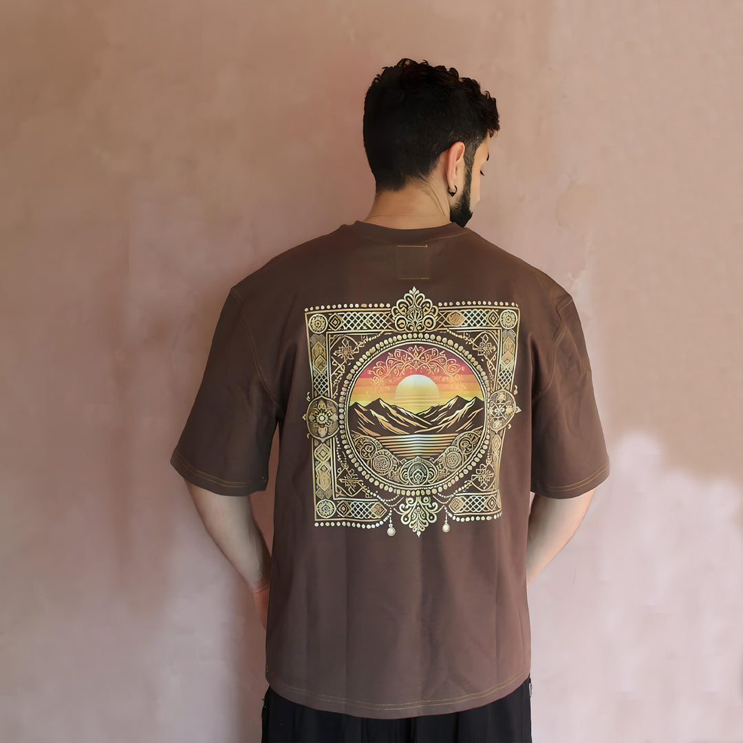 This back view of the oversized brown caftan t-shirt features an artistic design of a sunset over mountains, framed with traditional Moroccan motifs. The detailed print captures a sense of wanderlust and heritage, making the piece stand out as a tribute to Moroccan aesthetics infused with modern streetwear style. The t-shirt's relaxed fit emphasizes comfort without compromising on style.