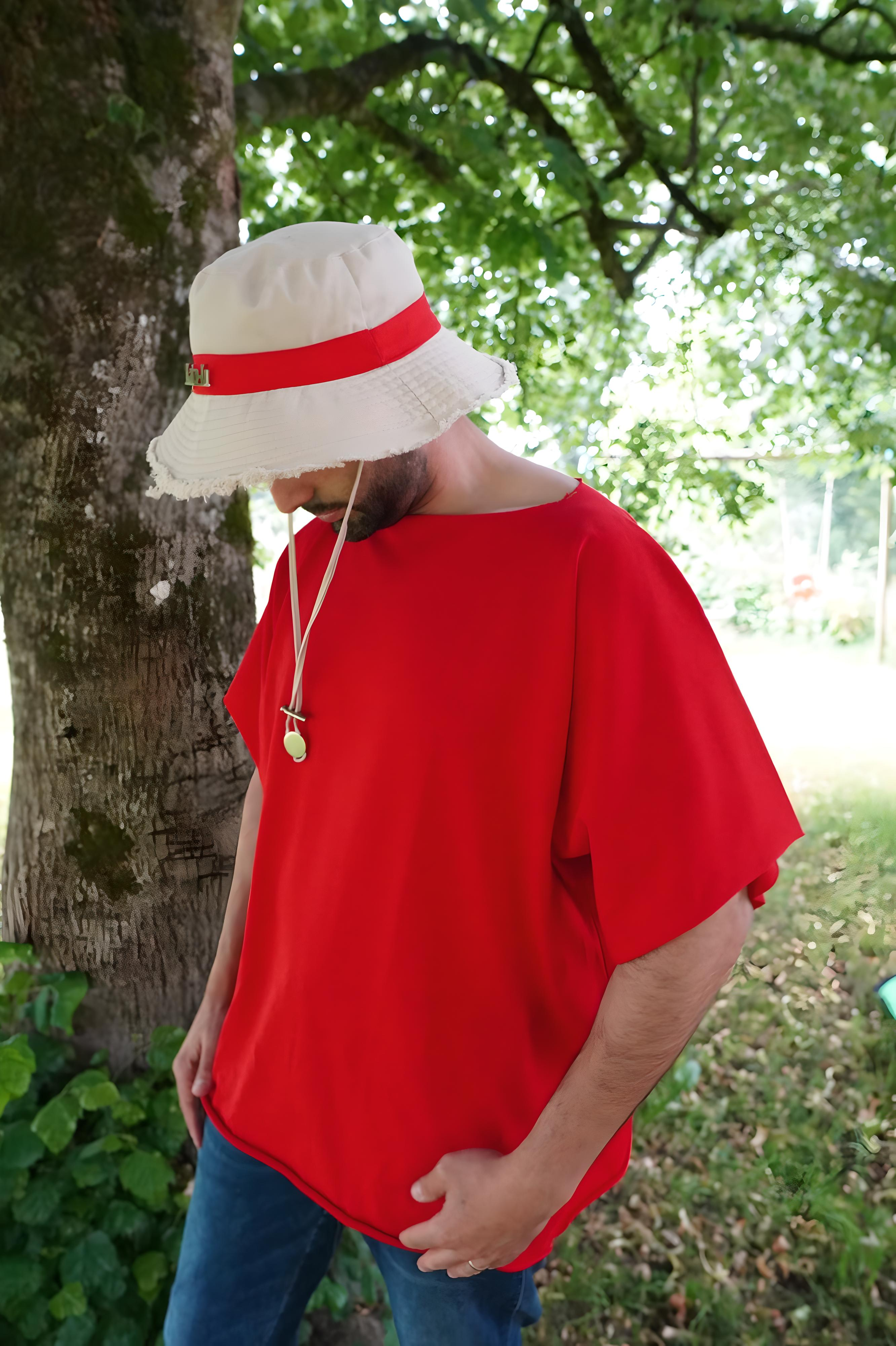 Vue latérale gauche du modèle avec le t-shirt oversize rouge, mettant en avant la construction droite sans finition d’ourlet.
