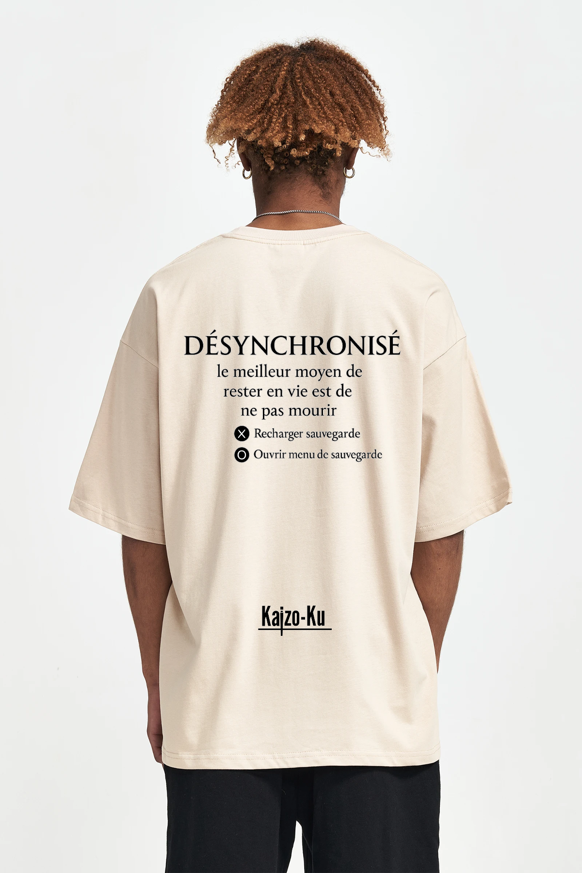 Jeune homme portant un t-shirt beige Kaizo-Ku avec impression texte gaming dans le dos