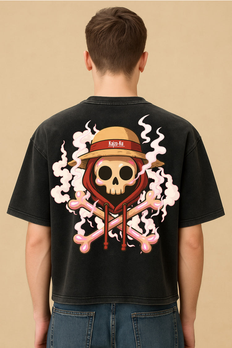 Vue arrière du modèle portant le t-shirt crop Kaizo-Ku, illustration dos avec tête de mort, capuche et chapeau de paille dans un style manga – décor studio fond sable.
