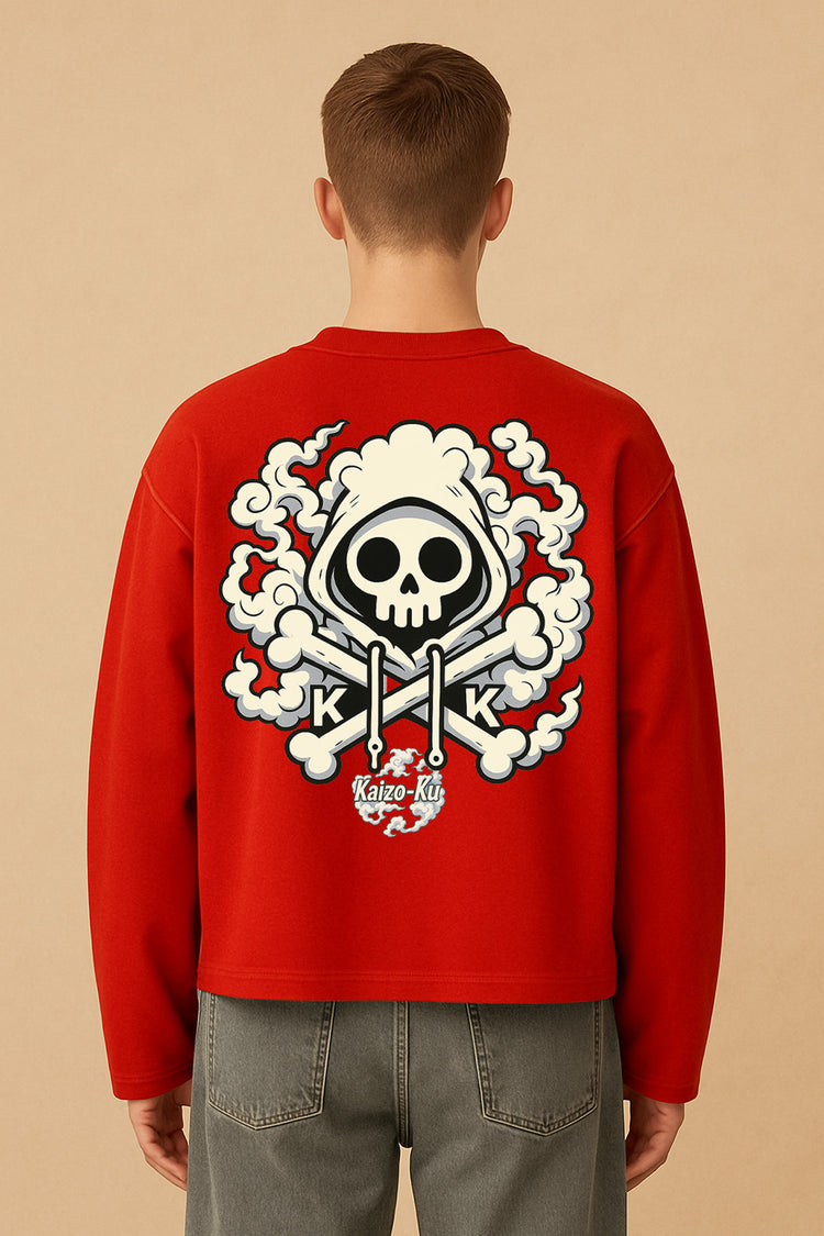  Vue arrière du modèle portant le t-shirt crop Kaizo-Ku, illustration dos avec tête de mort, capuche et chapeau de paille dans un style manga – décor studio fond sable.