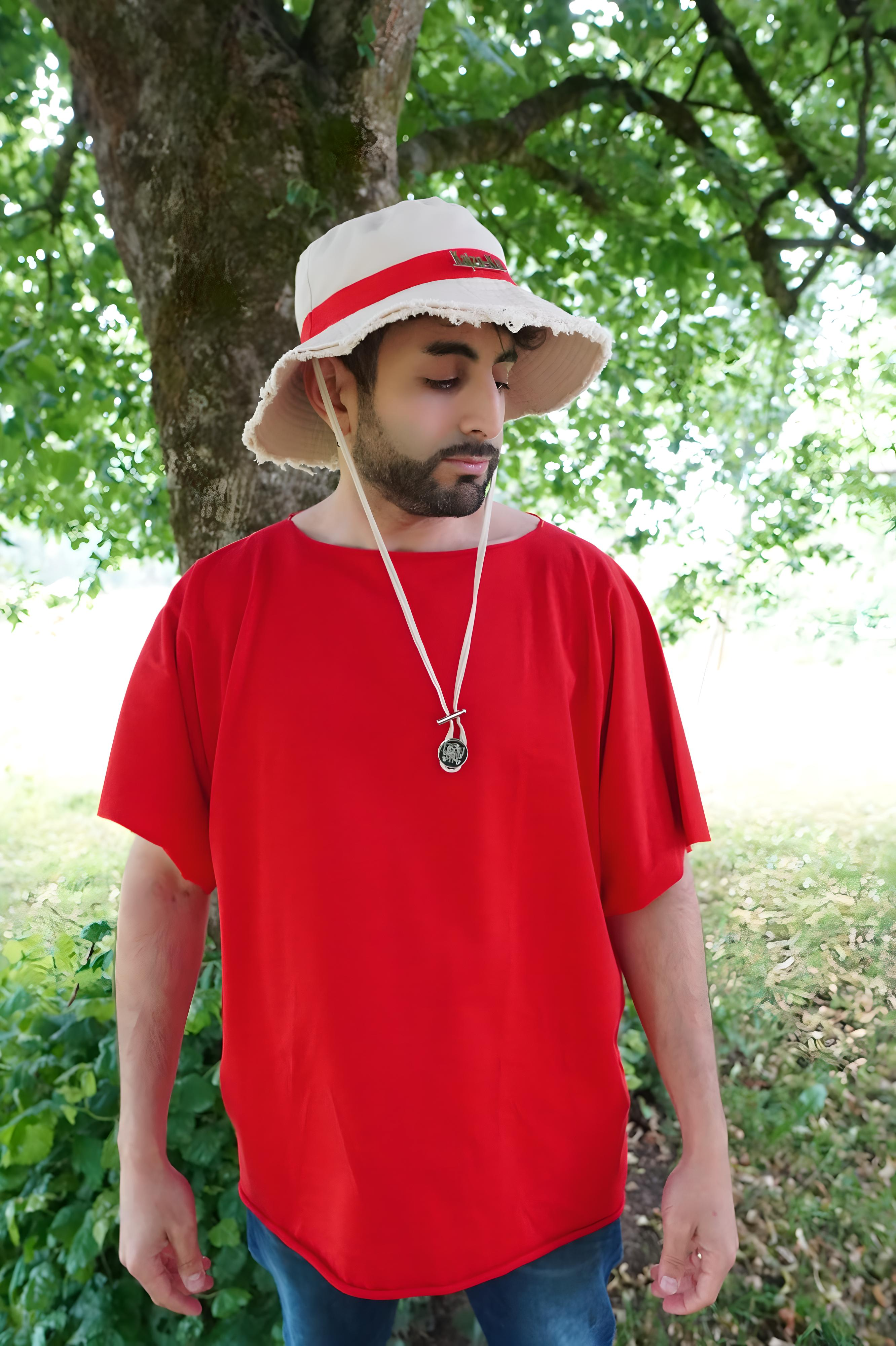 Modèle portant le t-shirt oversize rouge vif, col bateau, manches larges sans couture, accessoirisé d’un chapeau Kaizo-Ku et d’un médaillon inspiré de Luffy.