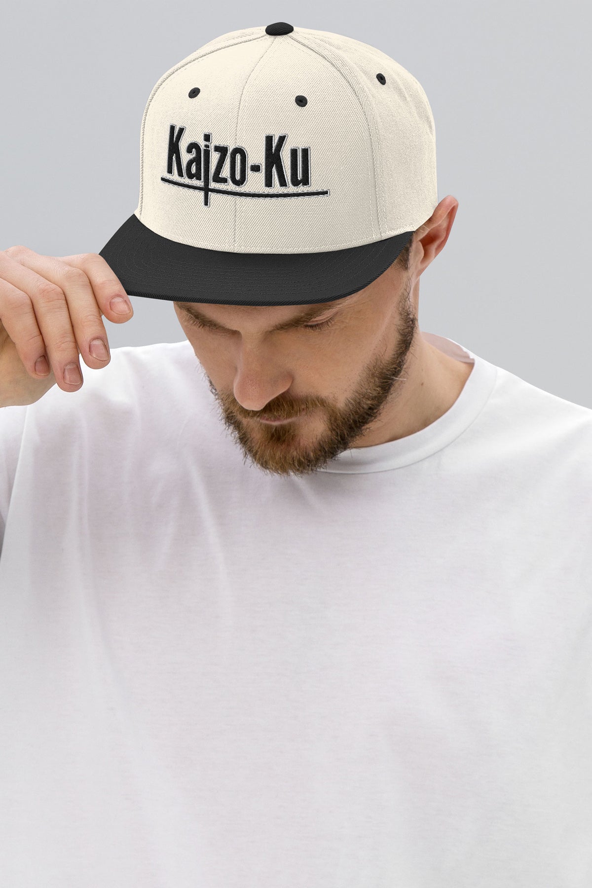 Male model wearing the Kaizo-Ku Snapback Cap, styled with streetwear, showcasing the cap’s fit and iconic branding.