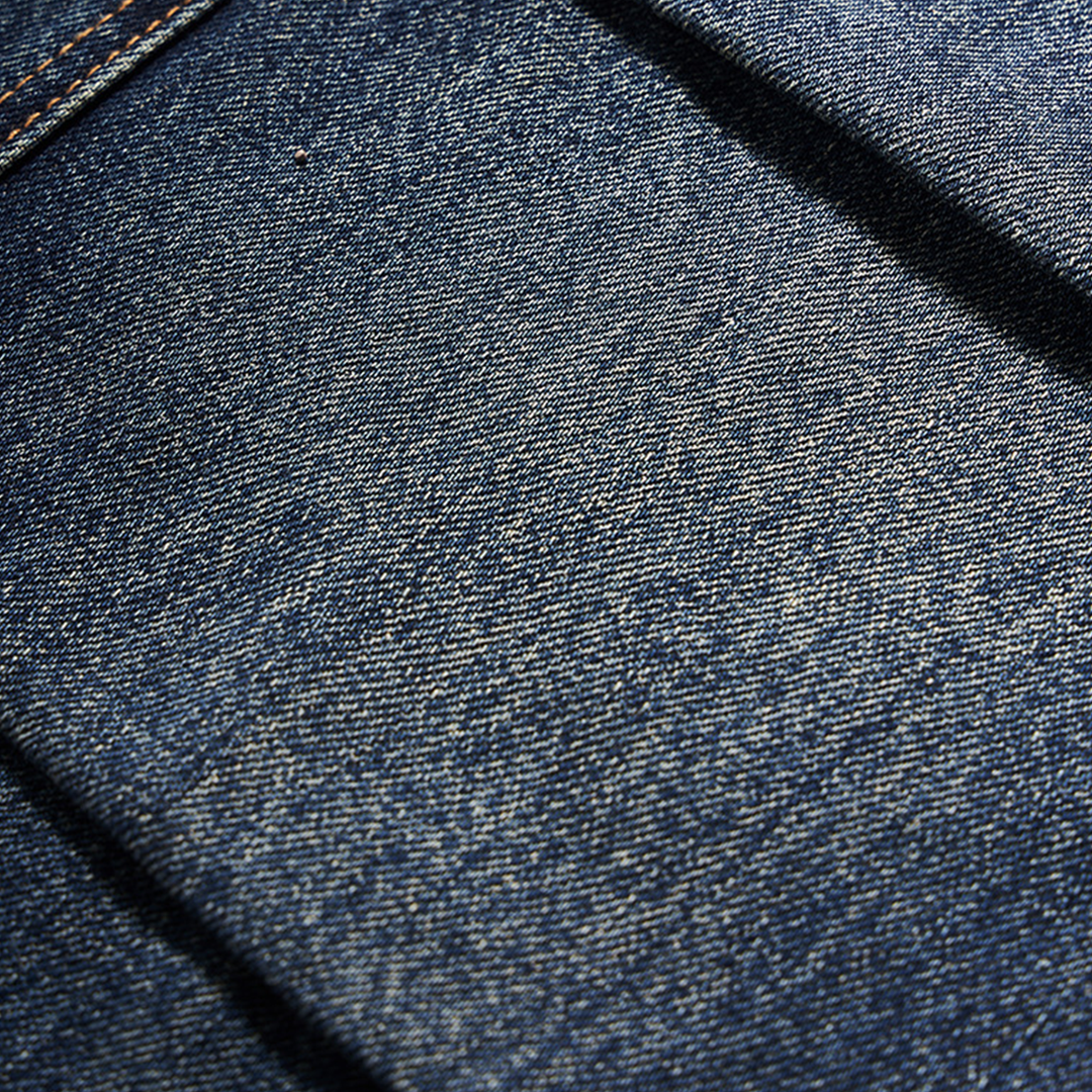 A close-up of the fabric texture on the deep indigo jeans, highlighting the premium quality and smooth finish.

