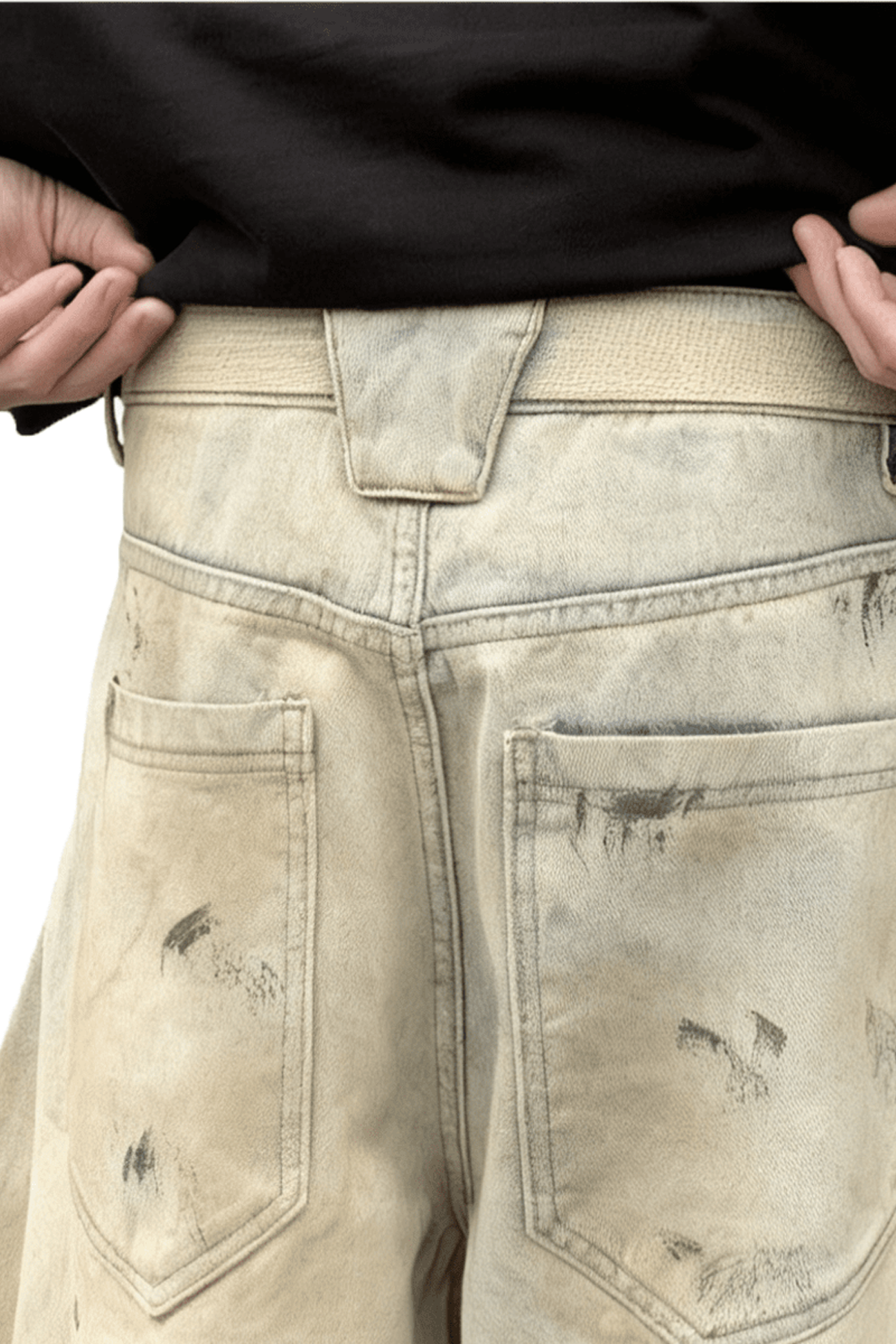 Close-up of beige distressed jeans with a plain background