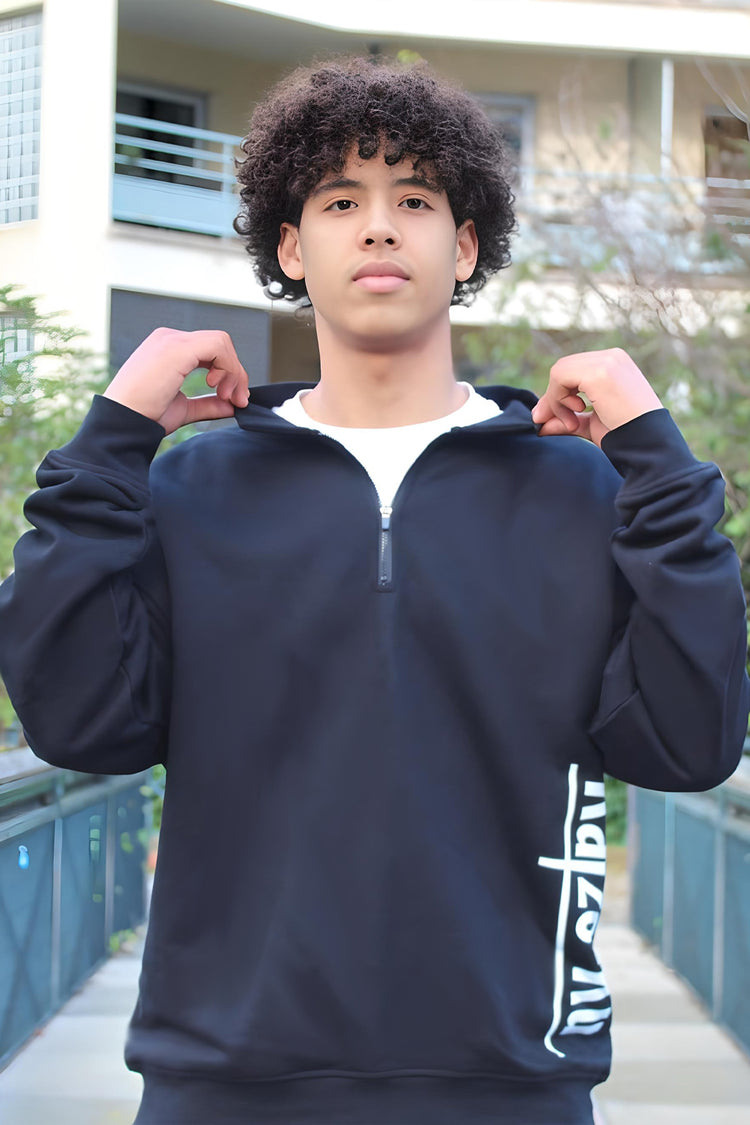 Model adjusts the collar of the black half-zipped sweatshirt, emphasizing its cozy, high-neck design.