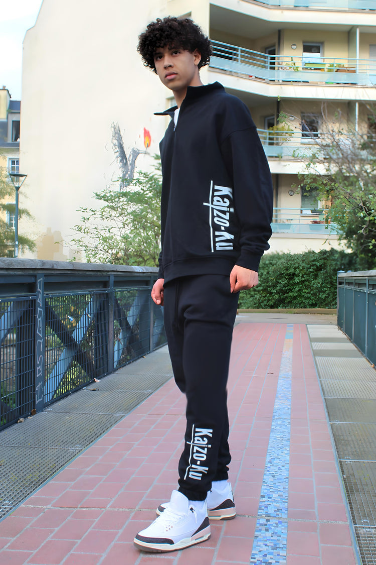 Full-body angled view of the model in the Kaizo-Ku black jogger, showcasing the jogger's relaxed, tapered fit within a modern, stylish ensemble.