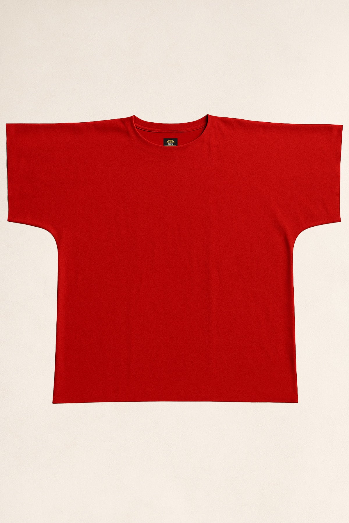 Vue à plat du t-shirt rouge oversize sans coutures, coupe droite minimaliste, posé sur un fond sable pour un rendu studio clair et épuré.
