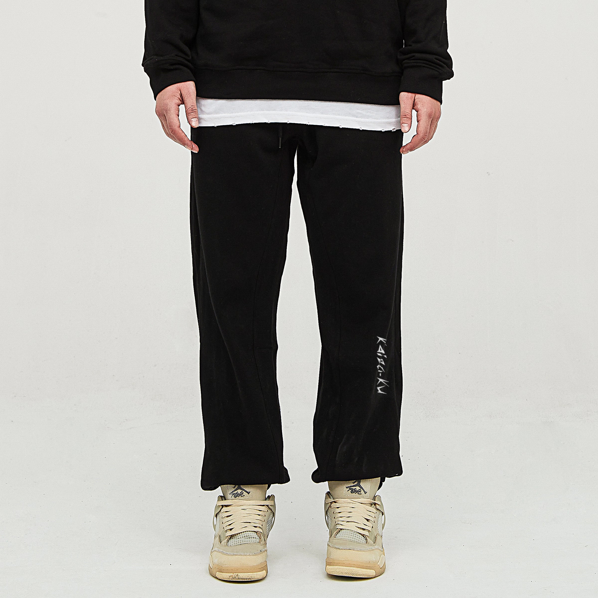 Model wearing the oversized jogger in Black from Kaizo-Ku. Relaxed fit with embroidered "Kaizo-Ku" logo on the left shin for a casual, street-ready look.