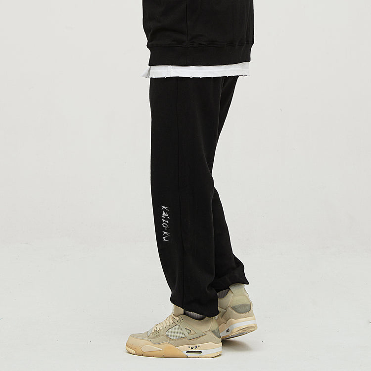 Close-up view of the model in the oversized jogger turned slightly left, showing the embroidered logo prominently on the shin. Perfect for highlighting the branding in a subtle, stylish way.