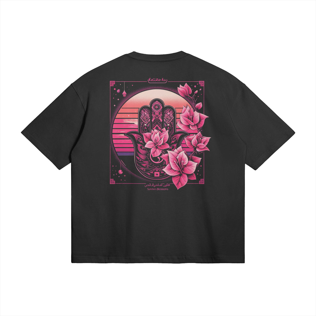 The back view of the Sunny Blossoms Oversized Summer T-shirt showcases the intricate Hamsa hand design with vibrant pink blossoms, set against a sunset backdrop. This unique artwork captures the essence of summer with its bold, eye-catching colors and intricate details, perfect for adding a touch of urban streetwear style to your look.