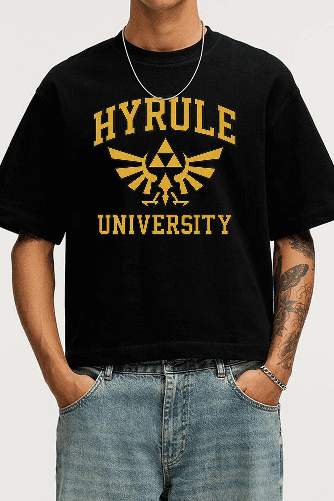 Homme portant un t-shirt noir Zelda Hyrule University, logo doré Triforce en style streetwear Kaizo-Ku.