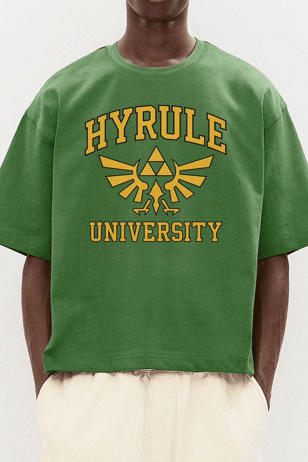 Homme portant un t-shirt vert Zelda Hyrule University, design doré Triforce, style casual streetwear geek.