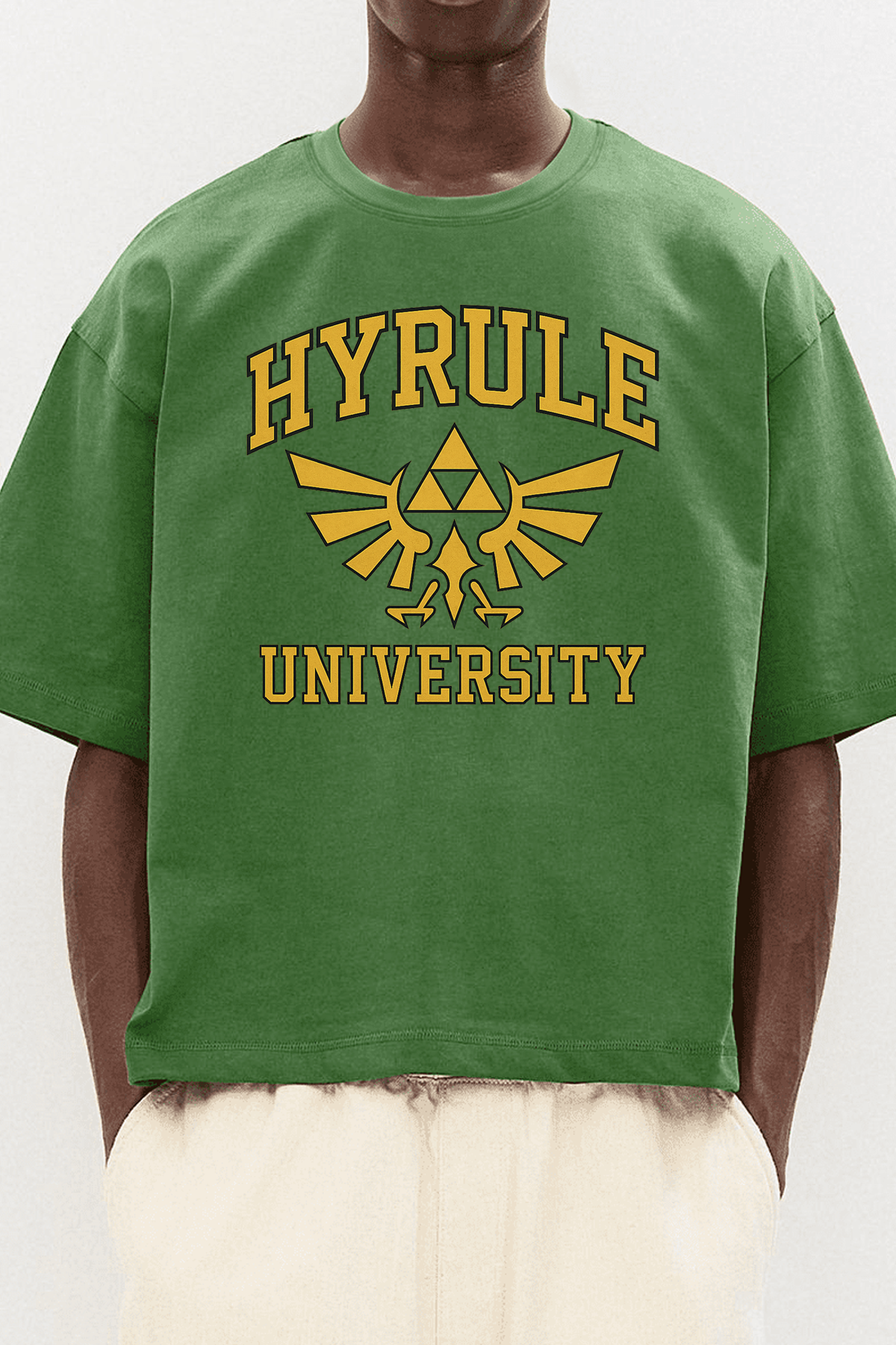 Homme portant un t-shirt vert Zelda Hyrule University, design doré Triforce, style casual streetwear geek.