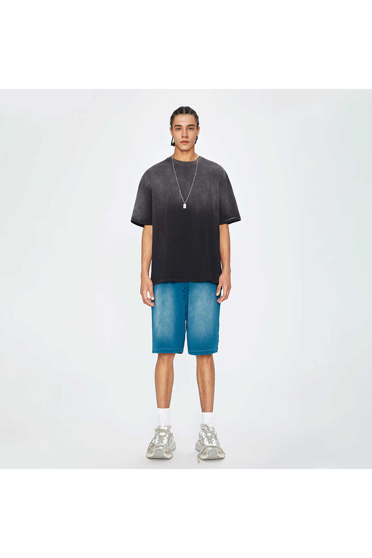 Jeune homme portant un t-shirt noir oversize Kaizo-Ku, coupe ample, col rond, style streetwear sombre