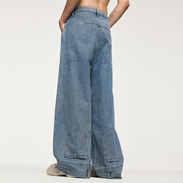 Back view of the model wearing the Kaizo-Ku Upside Down Denim Jeans without a shirt. The flipped pocket detail on the lower legs highlights the avant-garde design of these wide-leg jeans.