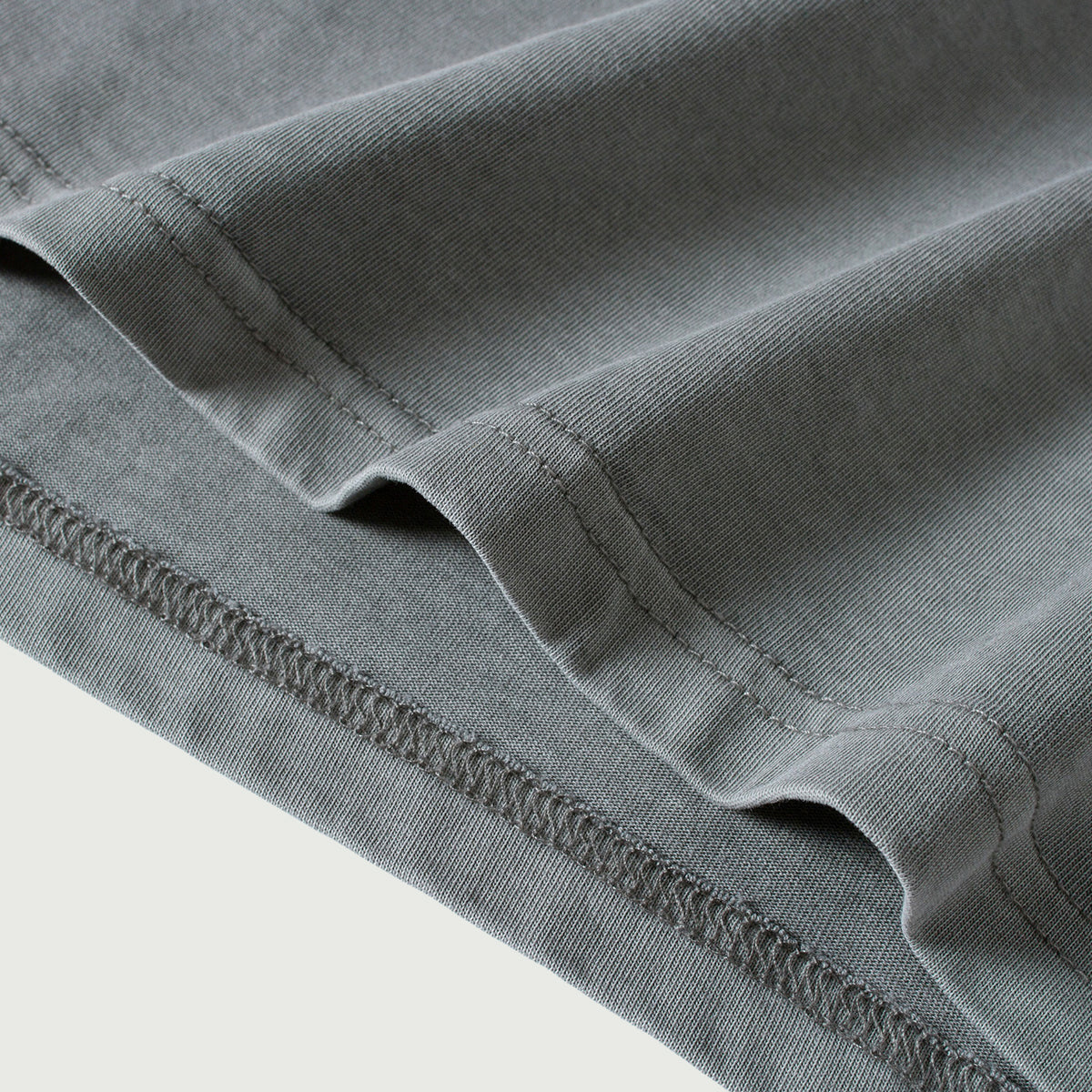 Close-up of the hem on the Kaizo-Ku oversized 2-in-1 t-shirt. Clean and minimalistic finish, enhanced by the subtle embroidered logo.